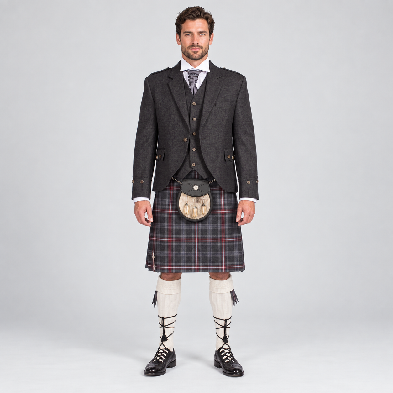 Men’s charcoal tweed Argyle jacket with matching waistcoat, Hebridean tartan kilt, sporran, cream hose and black ghillie brogues, front view.