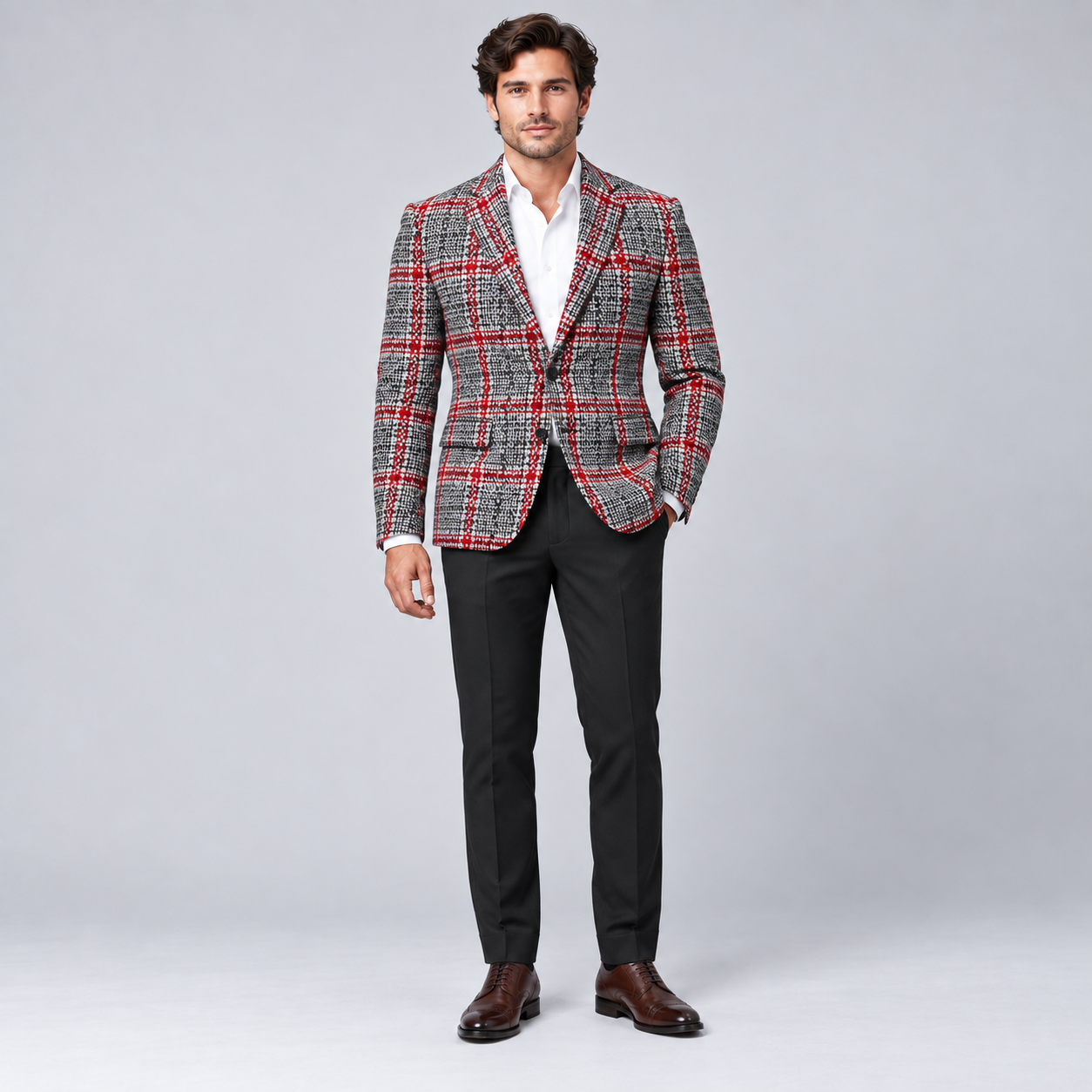 Male model wearing a grey, black and red Prince of Wales check wool tweed blazer with white shirt and black trousers.